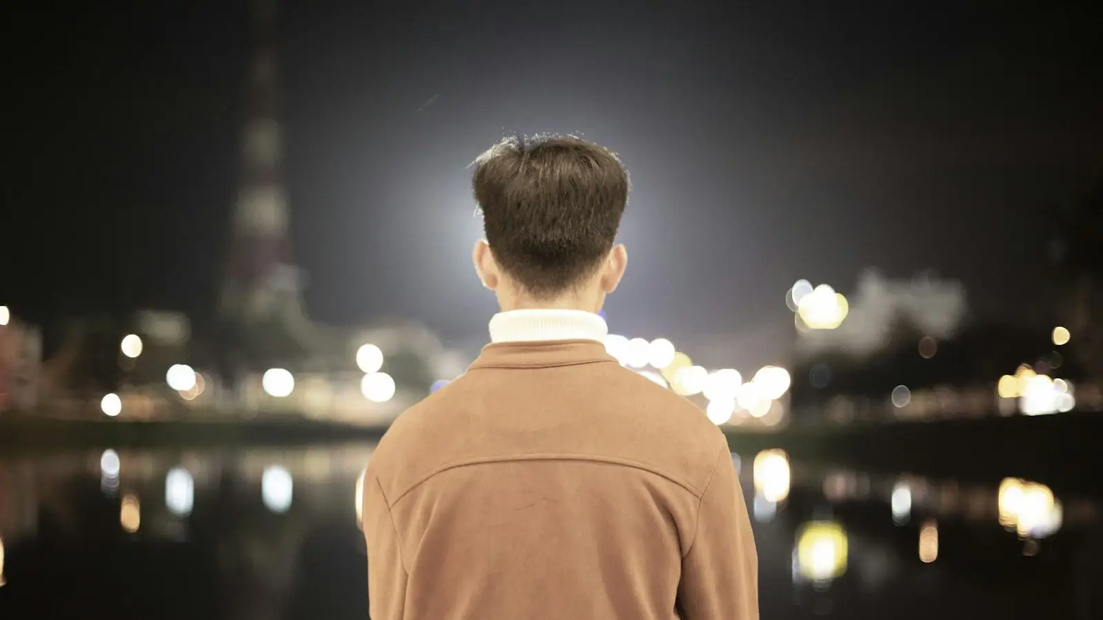 A man seen from behind in an evening city scene