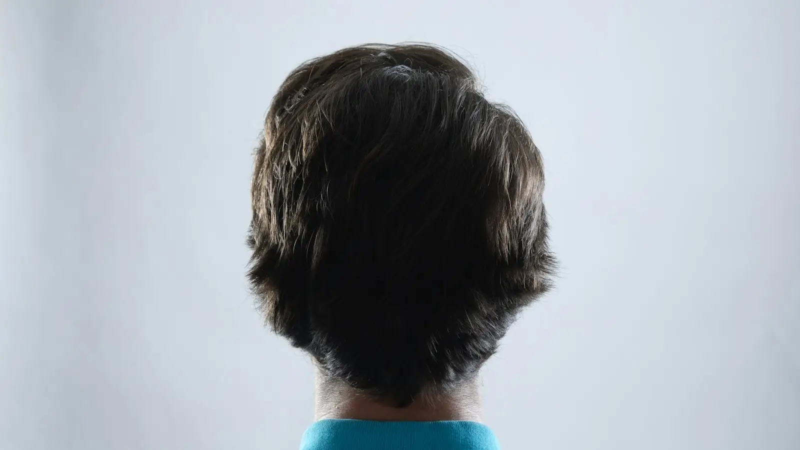 The back of a man's head showing his hair against a pale background