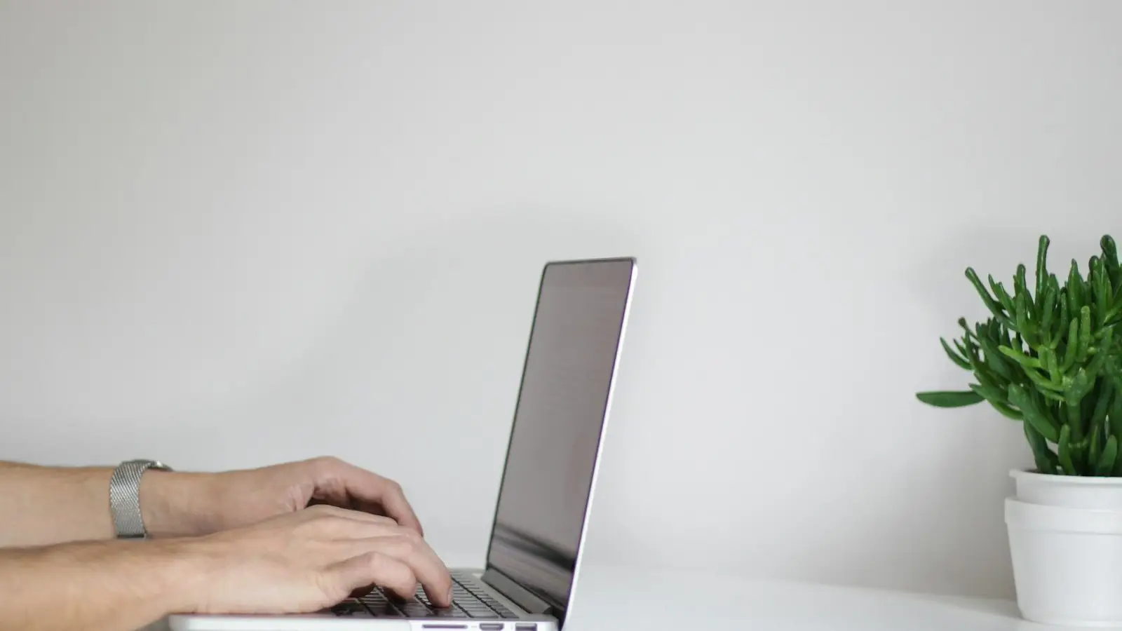Hands using a laptop on a desk