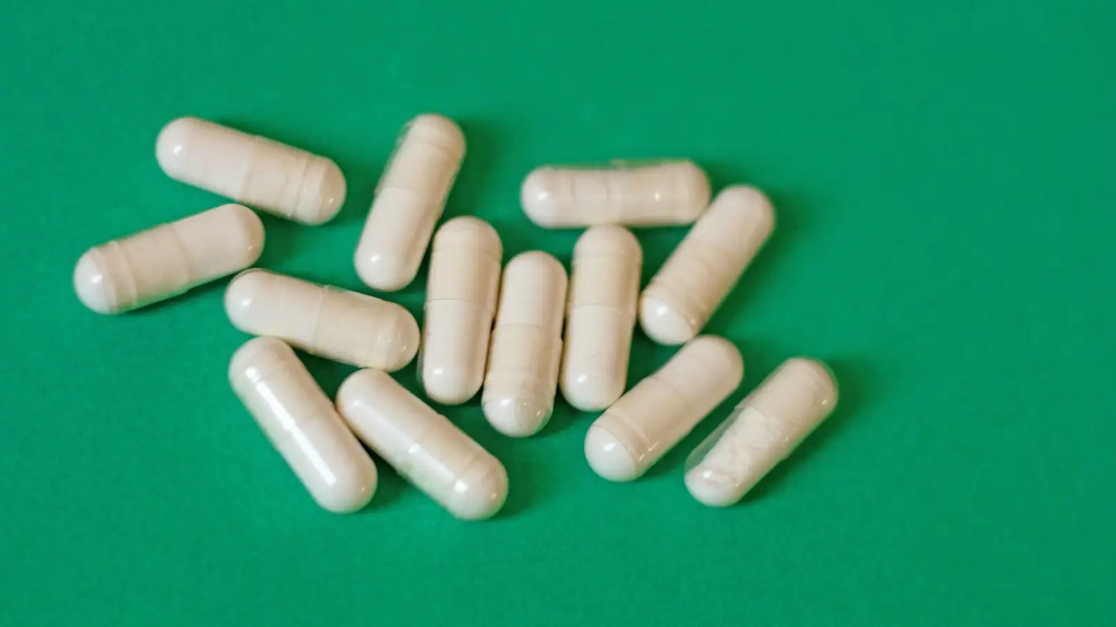 Plain white capsules on a green background